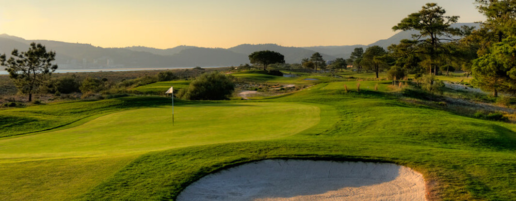 Troia Golf green guarded by bunker with view to the hills