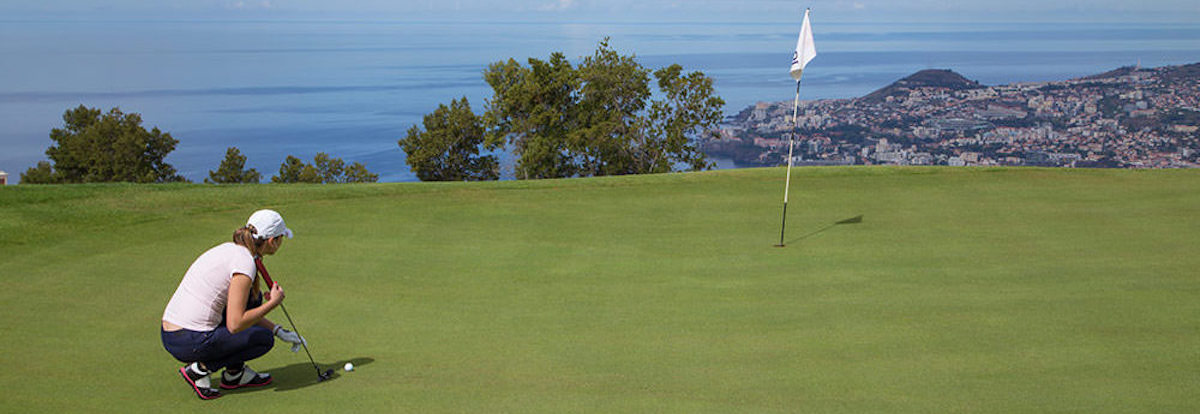 Lining up a putt on Palheiro Golf with view to Funchal and the Atlantic Ocean